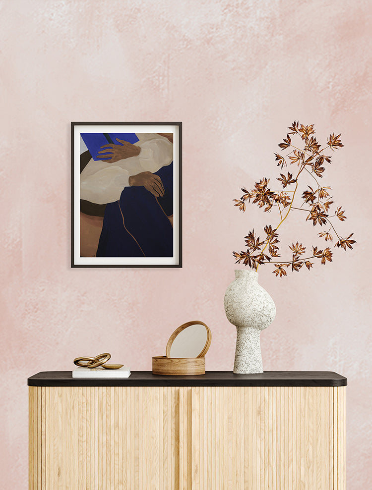 The room features Addison Chalk, Ombre Wallpaper in Blush Pink. A wooden console table holds a framed abstract artwork, a reddish-leaved plant, and decorative objects. The overall ambiance is modern and stylish.