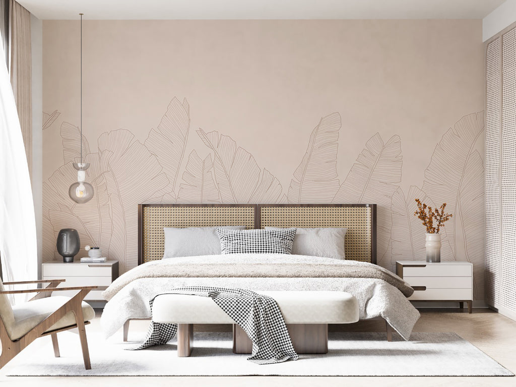 The room features large, Banana Foliage, Tropical Mural Wallpaper in Pink. A modern bed with white bedding and a throw sits against the botanical backdrop. Wooden side tables and minimalist decor complete the tranquil space. A woven headboard adds texture to the room