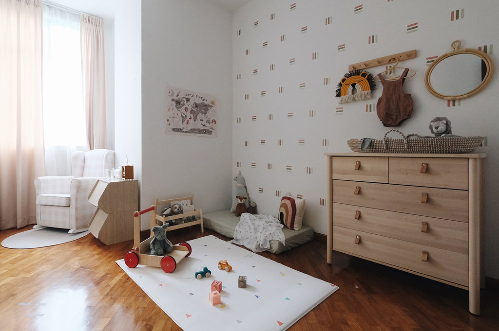 Minimalist children’s room with soft natural light. White armchair by the window, wooden dresser with toys, and a play mat.  Bold Lines, Wall Decals in Light Green - Dark Green - Brown.