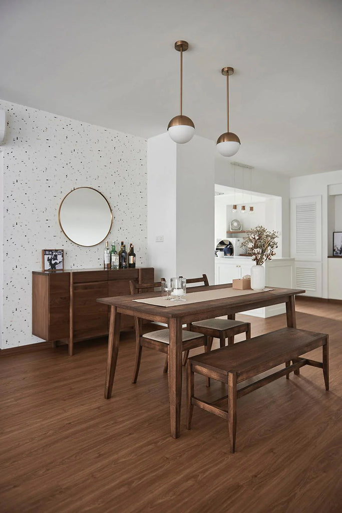 Contemporary dining area with Confetti Party, Patterned Wallpaper in Stratos Grey Blush Pink, adding a playful touch. Features a wooden table set, a sideboard with a round mirror, and pendant lights, creating a warm and inviting space.