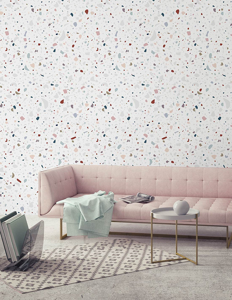 Stylish interior featuring Confetti Terrazzo, Pattern Wallpaper with multicolored speckles on a light background. Enhanced by a pink tufted sofa, modern tables, and chic decor for a trendy vibe.