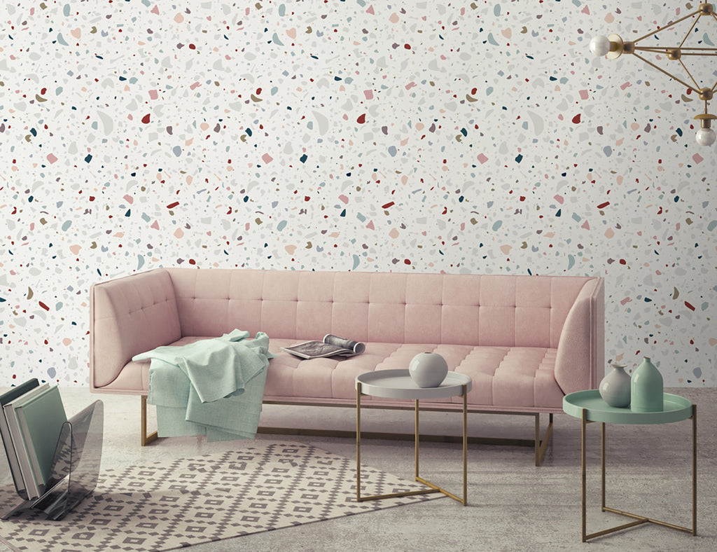 Stylish interior featuring Confetti Terrazzo, Pattern Wallpaper with multicolored speckles on a light background. Enhanced by a pink tufted sofa, modern tables, and chic decor for a trendy vibe.