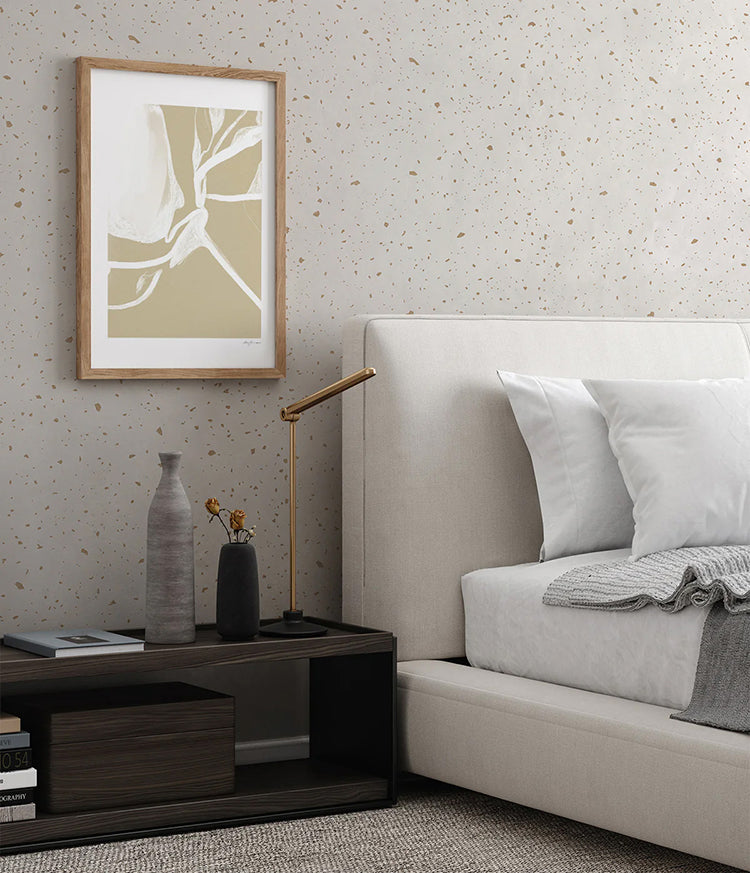 A stylish living room features modern furniture against a wall adorned with Gold Metallic Confetti Speckles, Pattern Wallpaper White. The space includes two sleek, curved grey armchairs, a plush, cream chaise lounge, and a round marble coffee table. A contemporary chandelier with spherical lights hangs from the ceiling, and minimalist decor items add to the elegant aesthetic. Light curtains frame the room, creating a soft, inviting atmosphere.