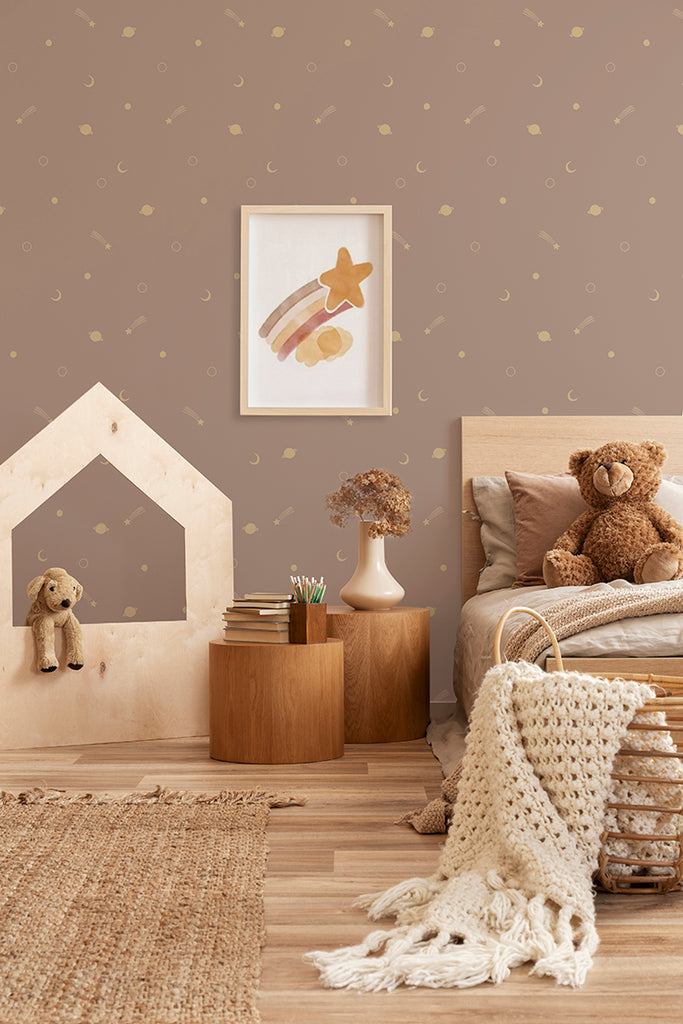 A cozy kid's room with wooden furniture and Gold Metallic Space Galaxy, Wallpaper in Pink. A plush teddy bear rests on the bed, while a playhouse stands in the corner, inviting imaginative adventures.