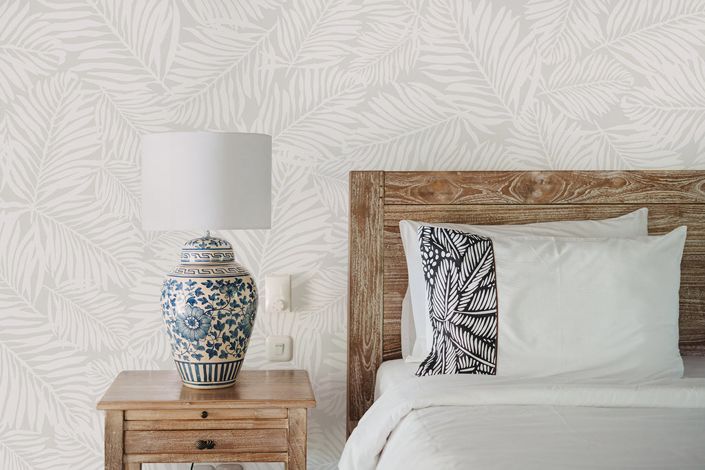 Elegant bedroom with Heather Fern, Pattern Wallpaper in Light Grey, featuring white and beige botanical design. Includes a wooden bed, white bedding, patterned pillow, and a classic blue and white porcelain lamp on a wooden nightstand.