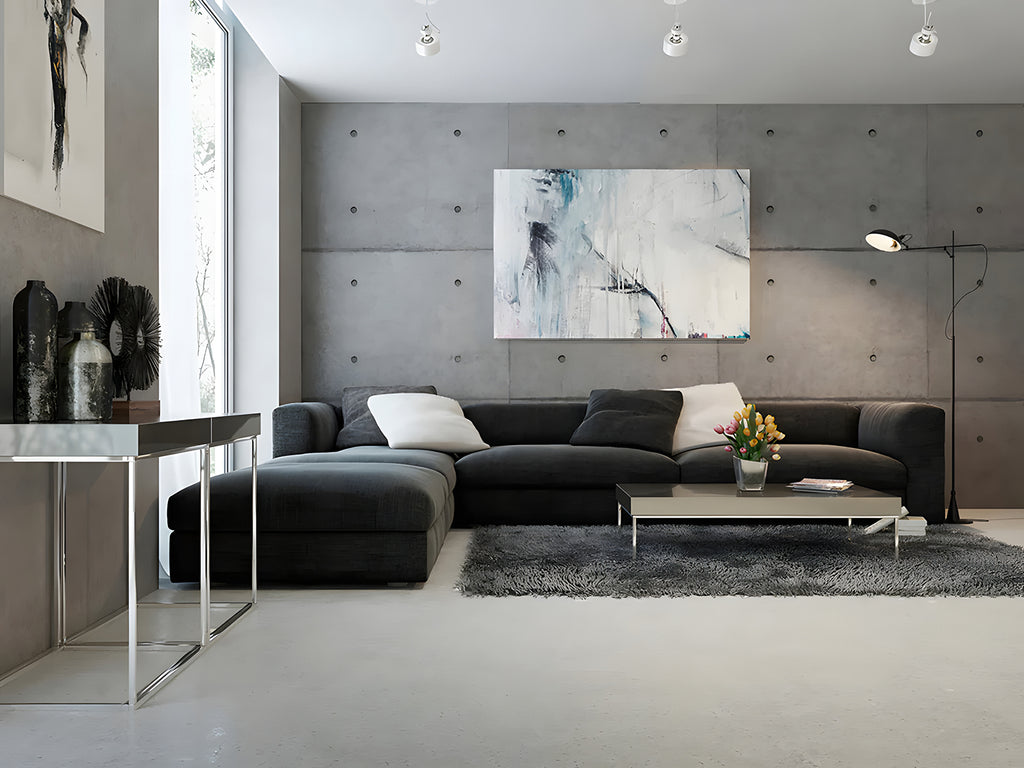 Modern living room adorned with the Industrial Concrete, Pattern Wallpaper. The room features a large, dark grey L-shaped sofa, a glass coffee table, and minimalistic decor, including abstract art pieces.