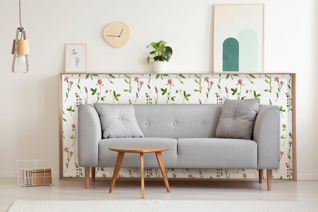 A cozy living room with a grey sofa, wooden coffee table, and minimalist decor. The room is accentuated by a floral pattern wallpaper named Lila, Floral Pattern Wallpaper, adding a touch of elegance.