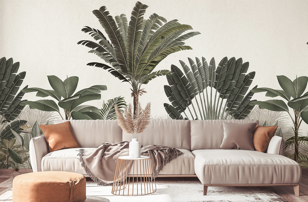 An elegant interior featuring a beige sofa with orange pillows, a small round table, and a tan ottoman. The Palm Paradise, Tropical Mural Wallpaper in Green, adorned with lush green palm leaves, adds a vibrant, exotic touch to the stylish decor.