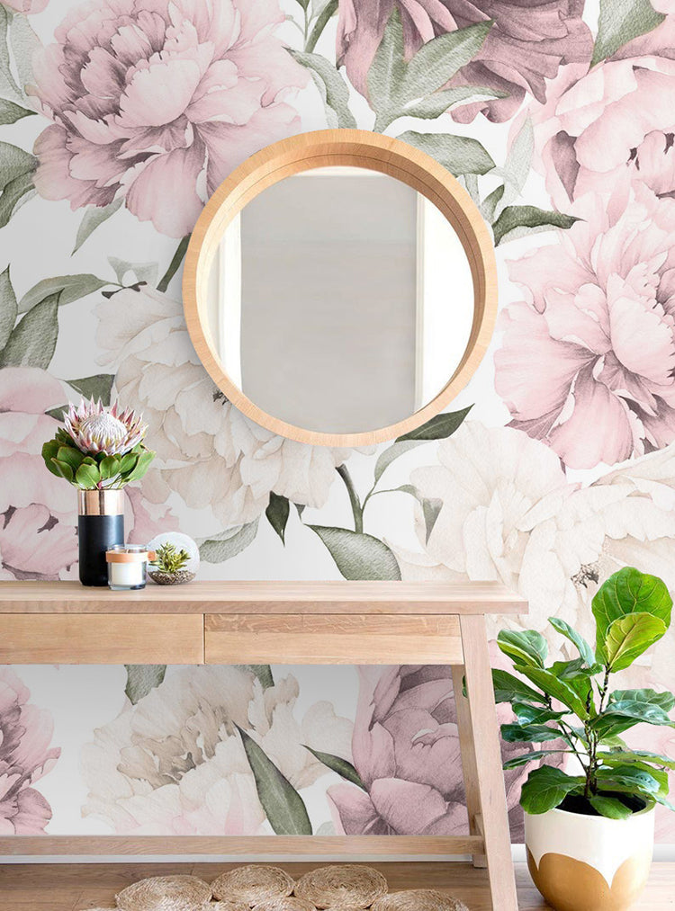Peonies Garden, Floral Pattern Wallpaper in Powder, featuring large powder pink peonies and pastel green leaves on a light background. A wooden mirror and console table with potted plants accentuate the serene ambiance.