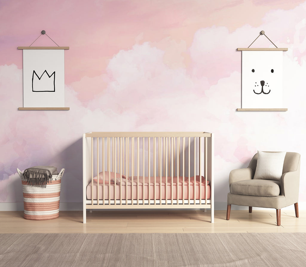 A tranquil nursery room adorned with a Pink Clouds Wallpaper, casting a soothing ambiance. The minimalist design features a crib, armchair, and framed animal art.