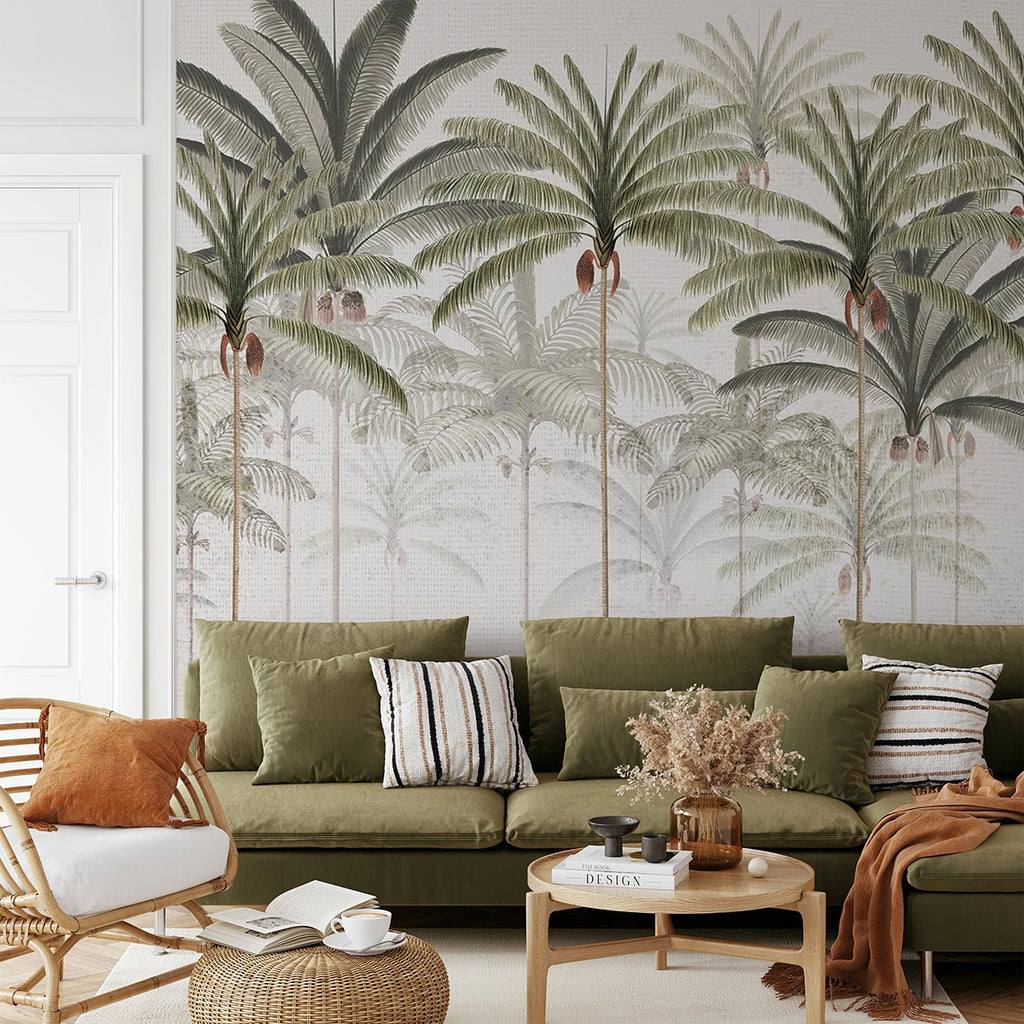 A tastefully decorated room, featuring a Rainforest Vintage, Mural Wallpaper in White . The room is adorned with a plush green sofa, a wooden chair, and a round coffee table. The wallpaper adds a touch of nature with its large palm leaves.