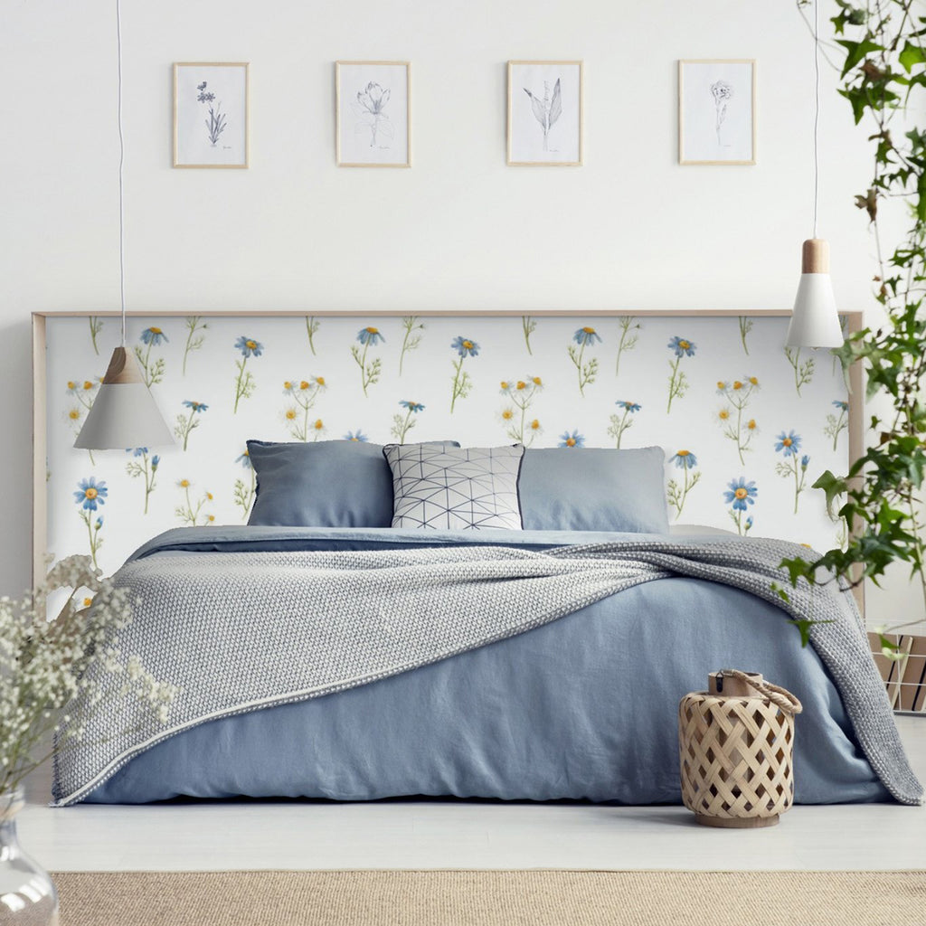 Sharon Floral Wallpaper adorning a bedroom wall, featuring a tranquil design of delicate flowers and birds. The room is furnished with a bed dressed in blue bedding, creating a serene and nature-inspired atmosphere.