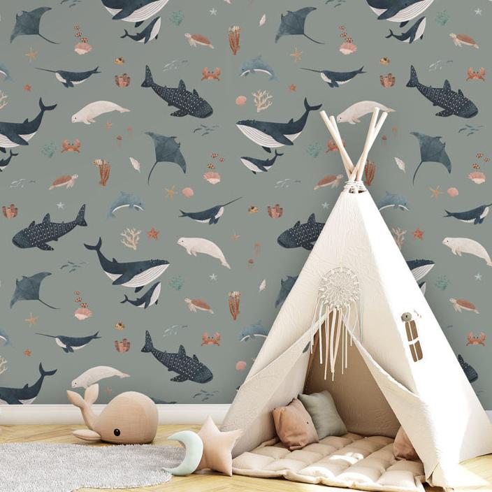 Splendid Sea, Pattern Wallpaper in a green, the children's room includes a wooden storage unit with drawers and leather handles, topped with decorative items like a wooden house and a stuffed snail toy. There is also a white teepee tent with a cushioned mat and a dreamcatcher hanging at the entrance, various toys like a wooden stacking toy and a star-shaped cushion, and a round, light-colored rug on the floor.