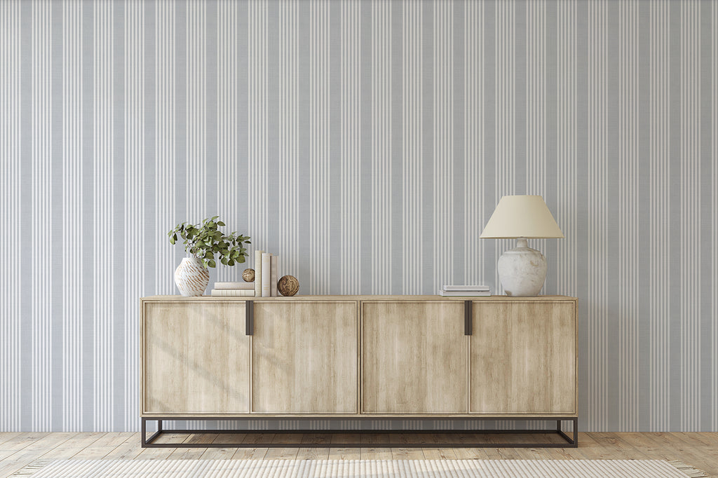 Minimalist room featuring Stripes Linen, Pattern Wallpaper in Grey Blue, a wooden sideboard with a lamp, a plant in a vase, and decorative items, creating a modern and elegant space.