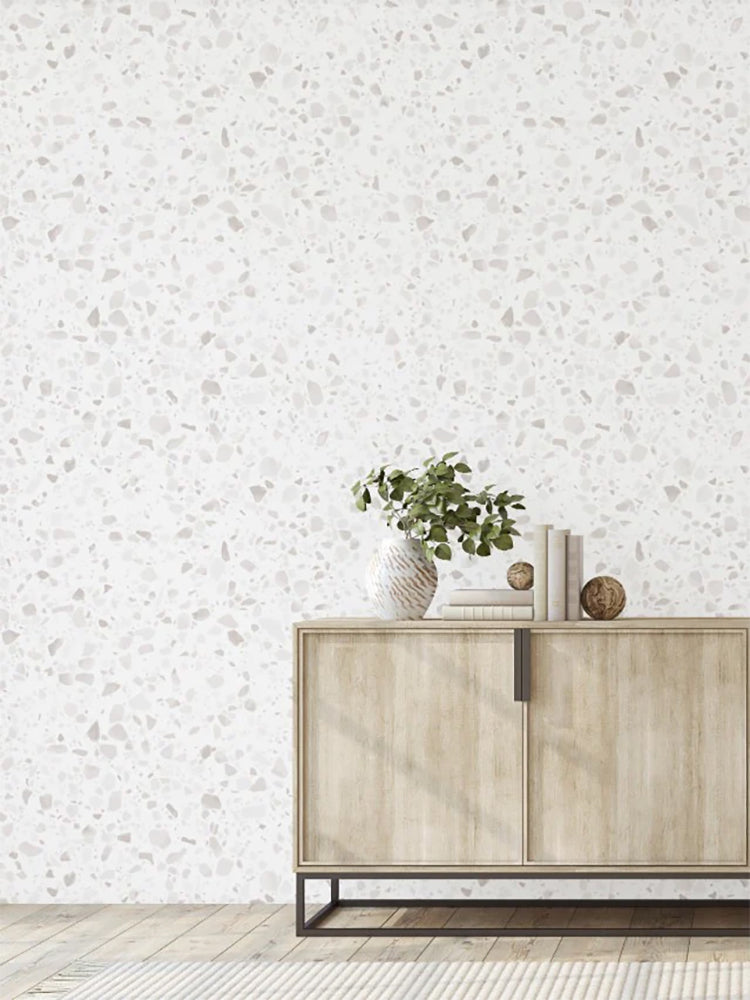 Minimalist room featuring Terrazzo Blanc, Faux Texture Wallpaper, a wooden sideboard with a lamp, a plant in a vase, and decorative items, creating a modern and elegant space.