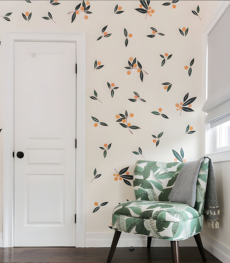 A cozy room with a white door, hardwood flooring, and a stylish chair featuring green leaf patterns. The vibrant Watercolour Oranges, Wall Decals and green leaves on the wall add a pop of color.