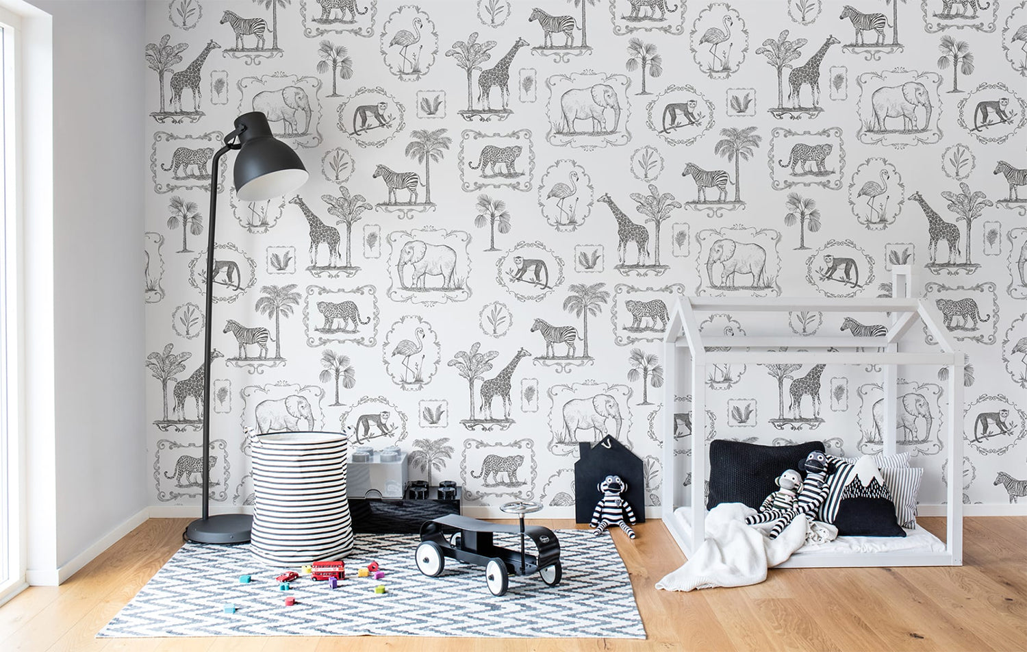 Animal Kingdom, Black & White Pattern Wallpaper featured on a wall of kid’s playroom with a wooden playhouse and patterned floor mat on a wooden flooring with scattered toys on the ground
