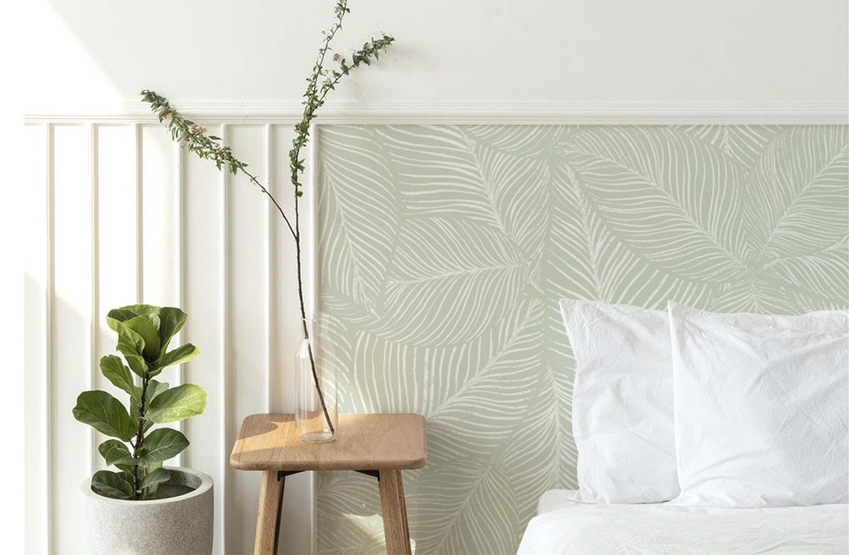 Noelle Fern, Tropical Pattern Wallpaper, in green as seen in a cozy living area with comfortable chair and soft pillows.