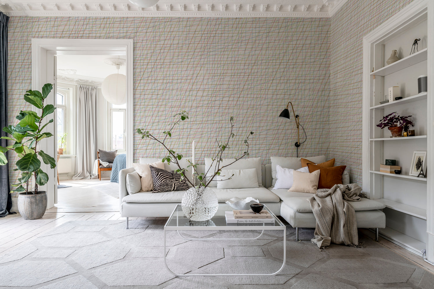 Note Sheets, Pattern Wallpaper featured on a wall of a bedroom with a living area with white sofas, multicolored pillows and sheets and glass table