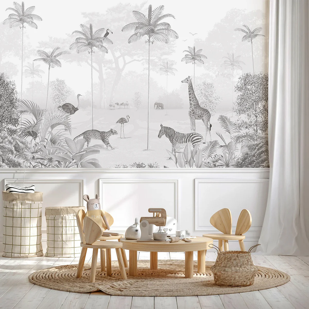 A cozy room with wooden flooring, a round table with chairs, and a shelf filled with toys. The wall features the Animal Paradise, Mural Wallpaper in Gray depicting a serene jungle scene
