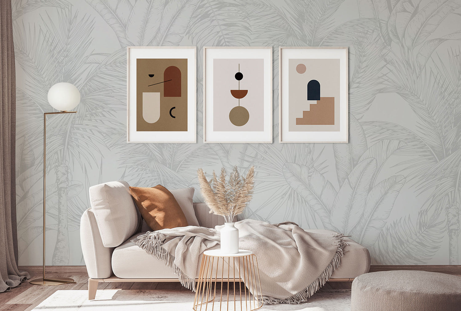 A tranquil living room with Tropics Botanical, Mural Wallpaper in Light Grey. A comfy sofa with a plush throw is under three abstract art frames.