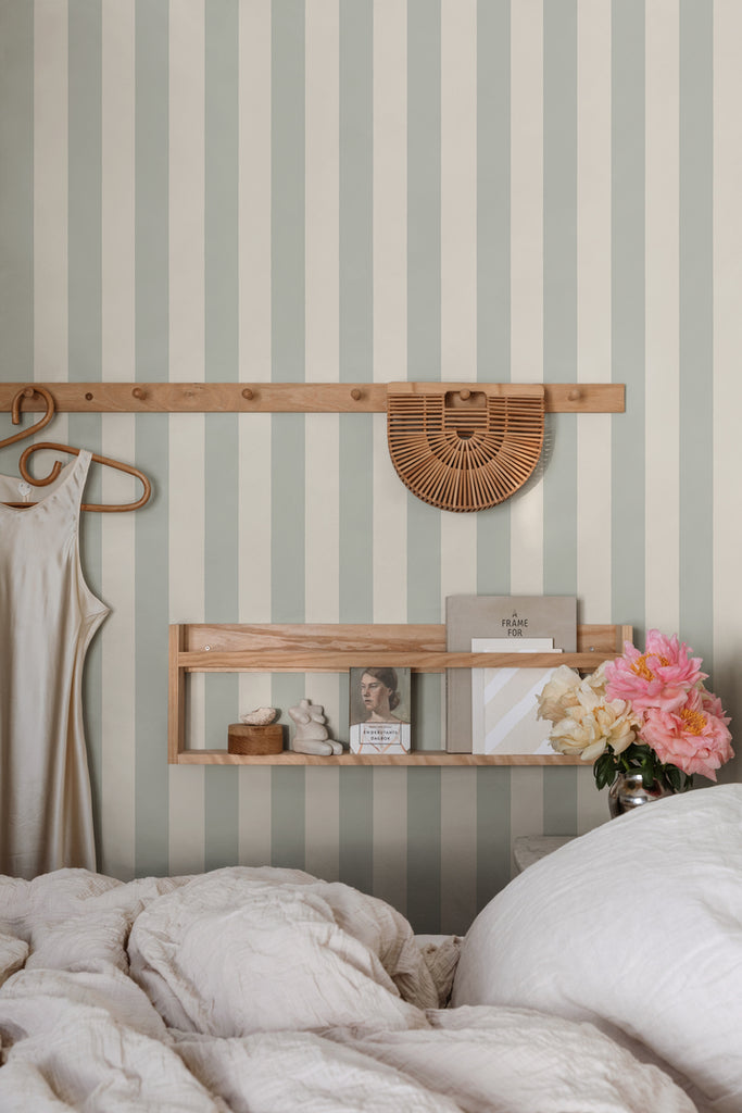 Teira Stripes, Wallpaper in Sage Featured on a wall of a bedroom with white sheets and pillows.